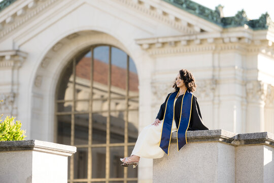 Proud college graduate seated near architecture