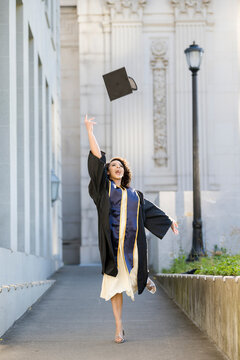 Excited Berkeley graduate tossing cap in celebration on campus