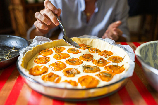 Hand with a spoon making an apricot pie on a wooden table