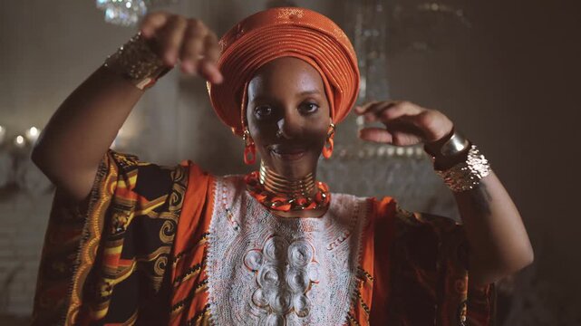 Seductive african woman in ethnic gown dancing and looking at camera, portrait. Unique culture and heritage of african continent, temptation and allure, diversity of female beauty and appearance
