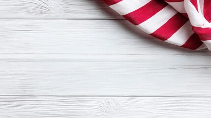 Obraz premium Red and white striped fabric draped over a white wooden background, top right corner