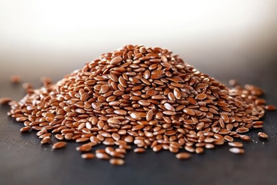 Close-up of a glossy brown flax seed pile on a dark surface, an earthy warm display of tiny edible seeds