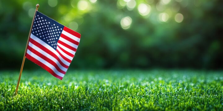 small american flag planted in fresh green lawn with sunlit bokeh background, peaceful patriotic mood