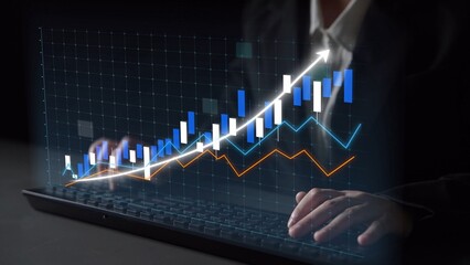 A close-up view of hands typing on a laptop keyboard while interacting with a digital graph...