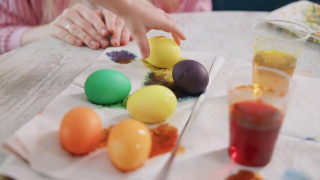 Small hands carefully paint eggs with vibrant dyes