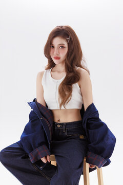 Young Asian Fashion Woman Sitting on Stool in Casual Denim Outfit Beauty Portrait on Clean Studio Background.