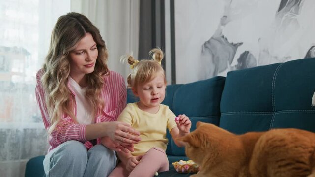 Couch scene with mother, toddler, and ginger cat