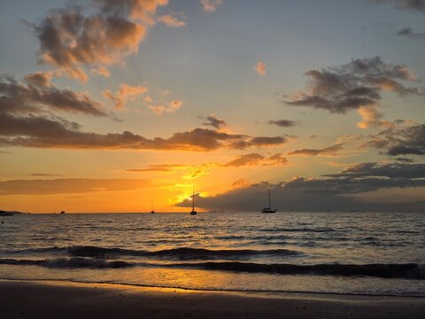 The Sunsets over the Beach with Sailboats on the Horizon