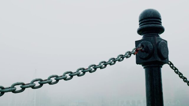 Iron chain and bollard in thick harbor fog
