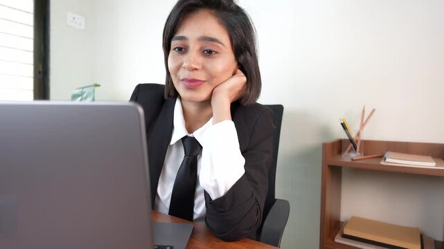 Close up of happy busy young Indian businesswoman boss manager sits on chair at workplace desk working on laptop reading emails analysing examine online data information.