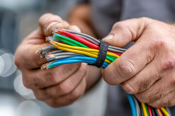 Hands fastening velcro strap around organized cable bundle in clean modern workspace
