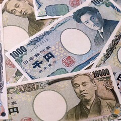 Japanese yen money bills pile on table. Japan banknotes of JPY currency close up. © Larysa