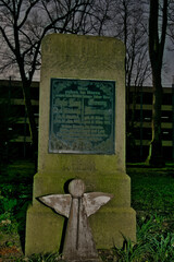 Ein von den Kindern gestellter Grabstein für die lieben Eltern mit einem Holzengel auf einem Friedhof in Unna © Blende8