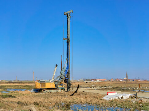 Industrial rotary drilling rig in open field under clear blue sky. Perfect for construction, engineering, geology, and infrastructure projects stock imagery. Shows heavy machinery in action, ideal for
