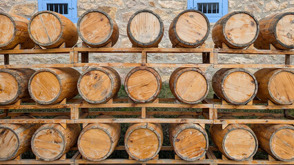 Fototapeta premium Wooden barrels full of fermenting beverages are neatly arranged on rustic wooden pallets, showcasing traditional craftsmanship and the aging process of alcohol in a historical setting