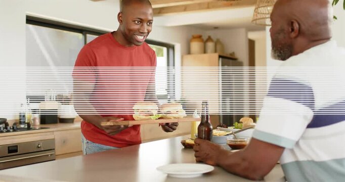 Adult son walking to kitchen island holding wooden tray and offering two burgers for family meal