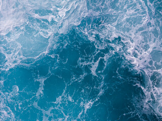 Obraz premium Aerial view of turbulent ocean surface with powerful waves and swirling water patterns