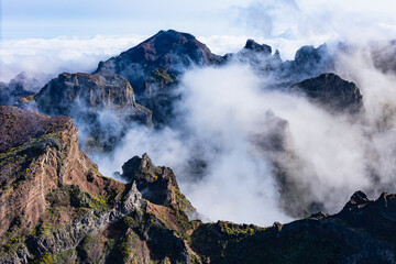 Fast moving clouds wrapping rugged mountain peaks near Pico do Arieiro, Madeira, aerial view