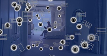 Sitting senior woman wearing robe, holding smartphone in bedroom by window, showing chat icons