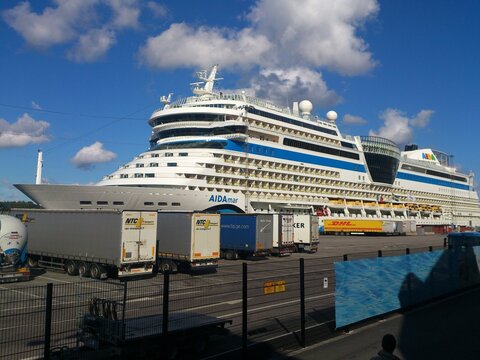 A large Sphinx-class cruise ship, AIDAmar, is moored at a Stockholm pier under a partly cloudy sky, 2016.