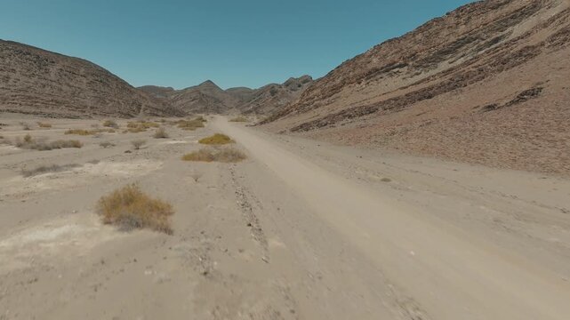 Aerial Drone Shot Flying Low Over Desert Road with Car and Rocky Mountain Landscape in Namibia