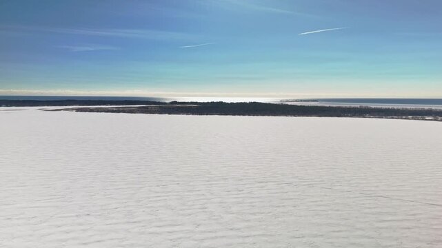 Aerial Drone View of Gosport in Brighton Ontario with Snow Covered Winter Landscape and Ice Over Water Under Blue Sunny Sky