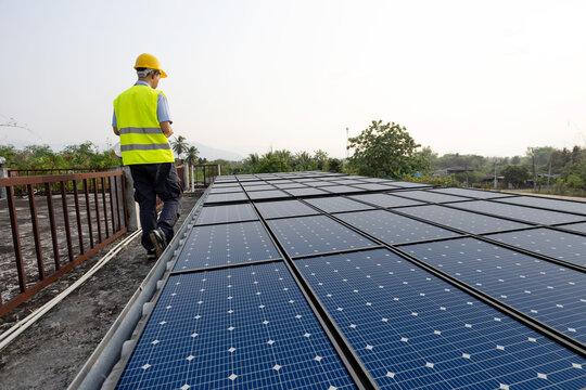 Technician inspecting rooftop solar energy system for renewable power and clean technology