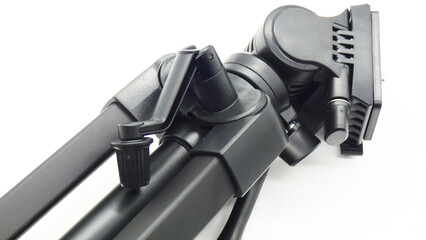 Black tripod lies on a white surface with a visible leveling head and legs