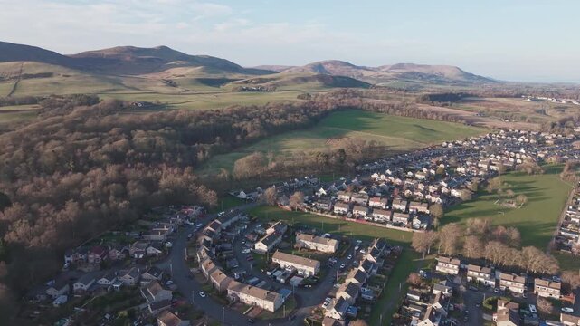 Aerial view of Penicuik town with the majestic Carnethy Hill in the background: Scenic drone flight over Midlothian countryside towards the Pentland Hills