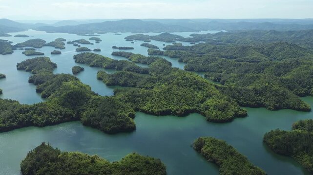 Drone flyover of Ta Dung Lake on a sunny day, showing green, forested islands across the lake in Dak Nong, Central Highlands Vietnam. Scenic aerial view of tropical nature.