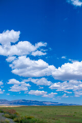 Obraz premium Panoramic view of sky with clouds over green field. Beautiful landscape with fluffy clouds.