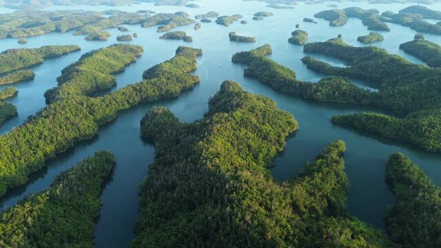 Drone pull-away revealing nearly symmetrical green islands on Ta Dung Lake in Dak Nong, Central Highlands Vietnam. Scenic aerial view of tropical lake landscape.