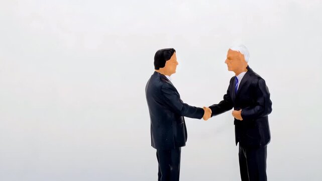 Two Miniature Businessmen Shaking Hands