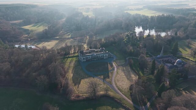 Cinematic drone shot of the abandoned Old Penicuik House: Majestic ruins of a Scottish manor house surrounded by autumn fields and forest