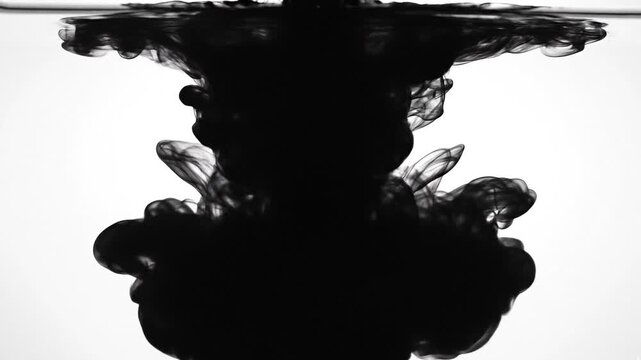 Dark liquid gold being poured into water creating a swirling effect