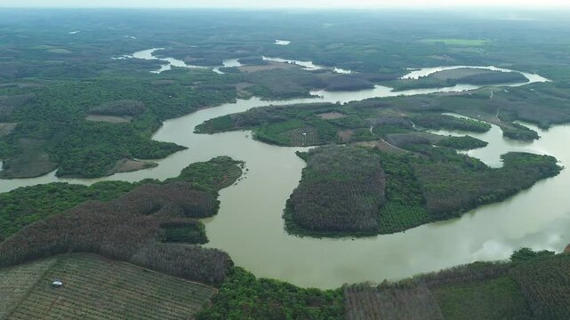 Aerial drone over patchwork farmland with a meandering river in a cloudy afternoon. Southern Vietnam