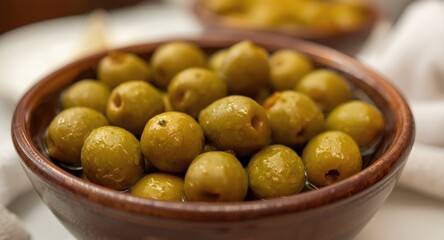 Close perspective on a bowl showcasing healthy green olives positioned on a dining table