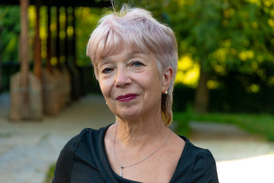 Senior woman 65 years old standing in park looking at camera