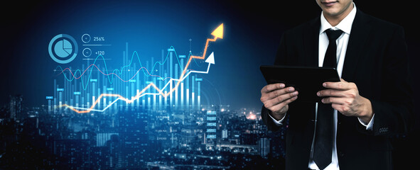A businessman stands with a tablet in hand against an urban skyline, surrounded by glowing financial growth charts and data analytics, showcasing success in modern finance. Scalp © InfiniteFlow