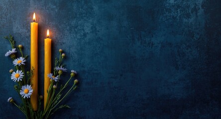 Rustic vertical scene showing beeswax candles alongside cornflowers on dark blue textured background with space for text
