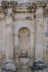 Fototapeta premium Ornate carved stone niche with spiral columns and decorative shell motif on the historic façade of the Alamo mission in San Antonio, Texas, showing weathered Spanish colonial architectural details.