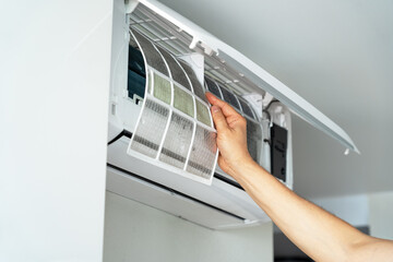 Close up of hands changes cleaning filter in air conditioner. Air conditioning maintenance. Purification and repair of cooling system