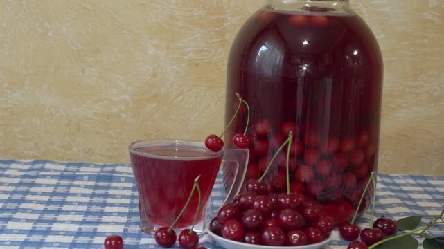 Homemade cherry compote in a glass jar on a tablecloth, Traditional cherry preserve in a jar