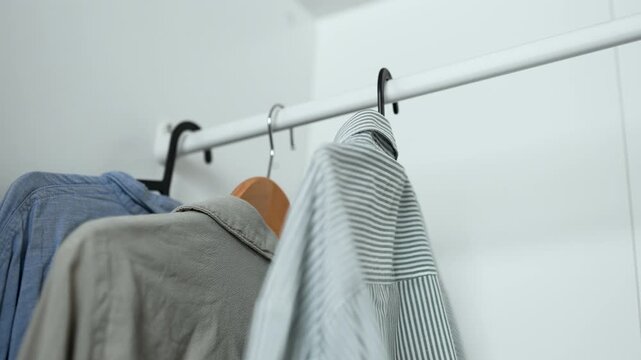 Hands hanging cotton shirts in organized closet, 4K 10-bit lifestyle footage