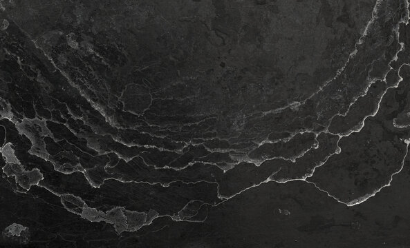 natural random pattern of undulating lines created by water drying on a dark surface 
