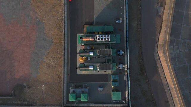 Rising aerial drone shot of a small BESS or Battery Energy Storage System storing electricity created by a nearby wind turbine on the Suffolk coast