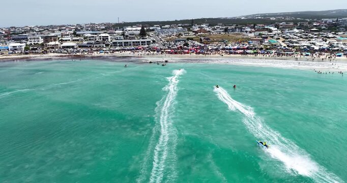 Drone aerial view of competitors racing inflatable boats during the Trans Agulhas Challengealong the turquoise coastline of Struisbaai in the Western Cape, South Africa.