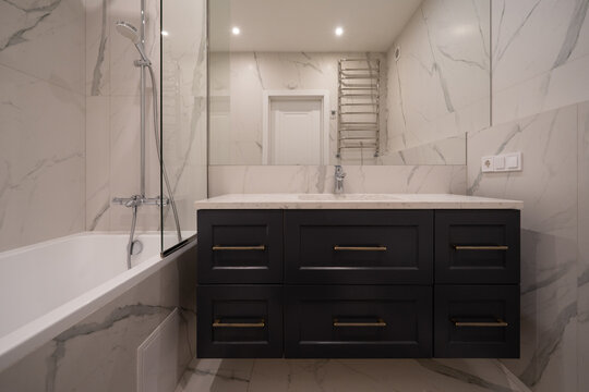 Modern bathroom with dark blue vanity and marble tiling