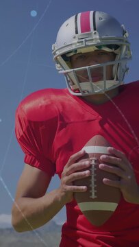 Vertical video: Football player raising hands tucking ball for pass as overlays moving across frame