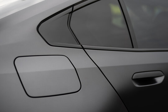 Close-up of the rear quarter panel, fuel door, and window trim of a matte grey car